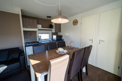 Essbereich mit Küchenzeile in einer Lodge, braune Stühle, Holztisch und moderne Annehmlichkeiten.