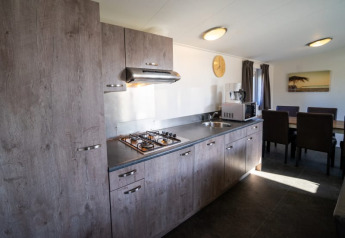 Moderne keuken in een lodge met houten kasten, gasvuur, dampkap, microgolf en eettafel in het licht.