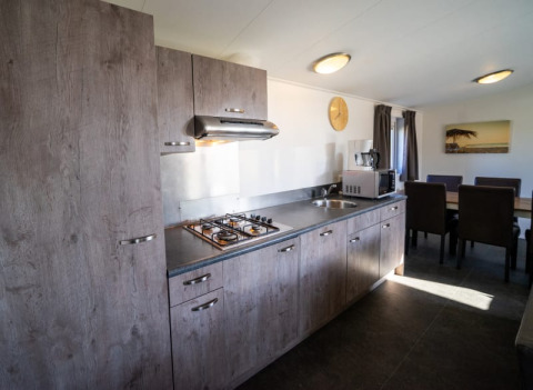 Cuisine moderne dans un lodge avec armoires en bois, gazinière, hotte, micro-ondes et table à manger.