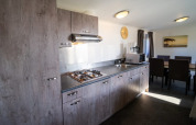 Modern lodge kitchen with wooden cabinets, gas stove, range hood, microwave, dining table and sunlight.
