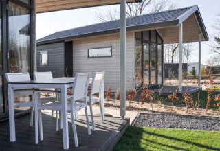 Outdoor terrace at a modern lodge with white patio furniture and a view of another lodge in the background.