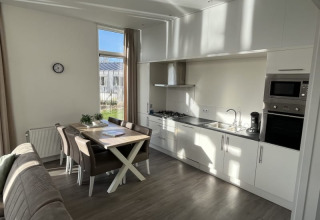 Cuisine moderne de lodge avec table à manger, chaises, canapé, grande fenêtre et appareils intégrés.