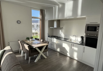 Cucina moderna in un lodge con tavolo da pranzo, sedie, divano, grande finestra e molta luce naturale.
