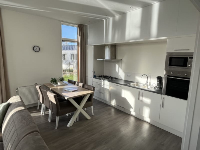 Cocina moderna en lodge con mesa de comedor, sillas, sofá, ventana grande y electrodomésticos integrados.