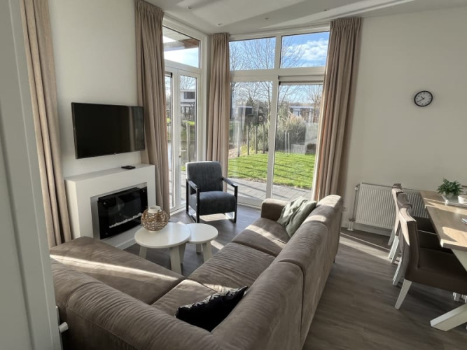 Sala de estar moderna de lodge con ventanales grandes, sofá cómodo y comedor con vista al jardín.