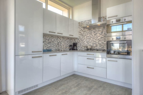 Moderne Küche in einer Lodge mit weißen Hochglanzschränken, Gaskochfeld und Einbauofen.