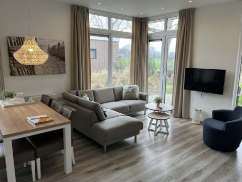 Modernes Lodge-Wohnzimmer mit Ecksofa, Esstisch, Flachbild-TV, großen Fenstern und Holzdekor.