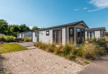 Foto einer modernen Lodge mit Kiesweg, grüner Bepflanzung und sonnigem Wetter unter blauem Himmel.