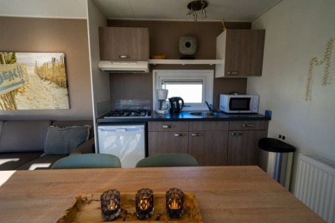 Kitchenette moderne dans un lodge avec réfrigérateur, micro-ondes, cafetière, plaque et coin repas cosy.