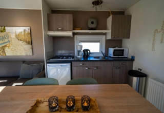 Cocina moderna en una cabaña con nevera, microondas, cafetera, estufa y acogedora zona de comedor.