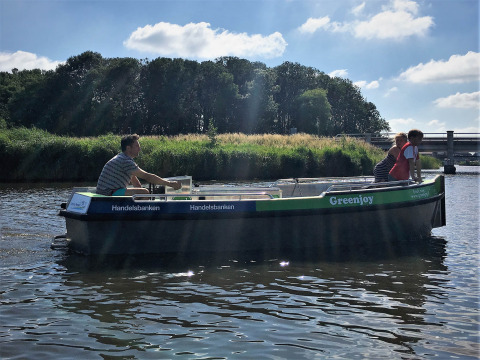 Paseo en barco con dos personas en un río en Camping Pasveer, Friesland, Países Bajos, rodeados de naturaleza.