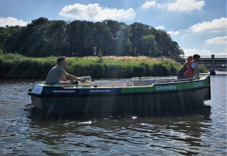Bådsejlads med to personer på en flod ved Camping Pasveer i Friesland, Holland, omgivet af natur.