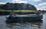 Paseo en barco con dos personas en un río en Camping Pasveer, Friesland, Países Bajos, rodeados de naturaleza.