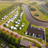 Aerial view of Camping Pasveer holiday park in Friesland, Netherlands with RVs, cabins, and moored boats.