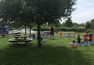 Bambini riuniti all'aperto a Camping Pasveer, in Frisia, Paesi Bassi, vicino a barche e al prato verde.