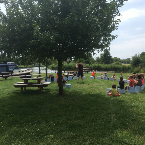 Bambini riuniti all'aperto a Camping Pasveer, in Frisia, Paesi Bassi, vicino a barche e al prato verde.