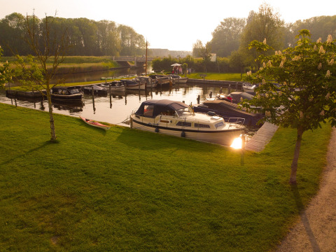 Barche ormeggiate e prato verde al Camping Pasveer, parco vacanze in Frisia, Paesi Bassi, al tramonto.