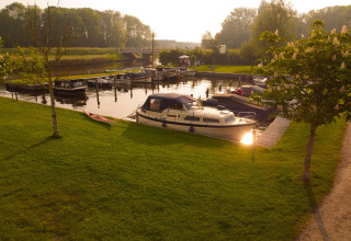 Barche ormeggiate e prato verde al Camping Pasveer, parco vacanze in Frisia, Paesi Bassi, al tramonto.