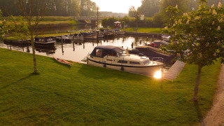 Barcos atracados junto al césped en Camping Pasveer, un parque de vacaciones en Frisia, Países Bajos.