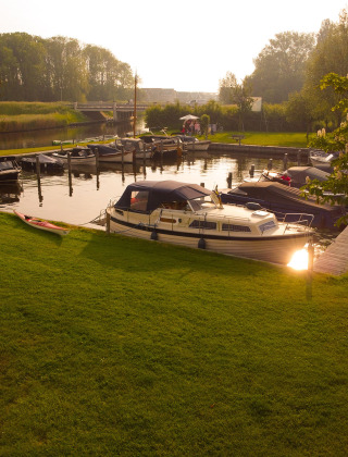 Barcos atracados junto al césped en Camping Pasveer, un parque de vacaciones en Frisia, Países Bajos.