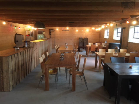 Espace commun convivial au Camping Pasveer en Frise, Pays-Bas, avec meubles en bois et guirlandes lumineuses.