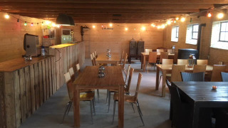 Acogedora sala común en Camping Pasveer, Friesland, Países Bajos, con mobiliario de madera y luces colgantes.