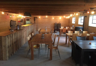 Accogliente area comune al Camping Pasveer in Frisia, Paesi Bassi, con arredi in legno e luci decorative.