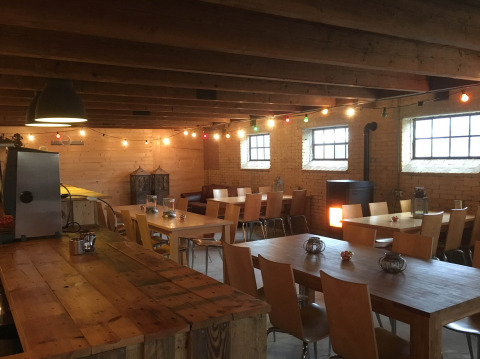 Zona pranzo accogliente al Camping Pasveer in Frisia, Paesi Bassi, con tavoli di legno, sedie e luci decorative.