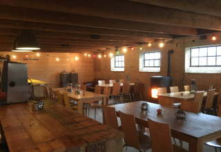 Cozy dining area at Camping Pasveer in Friesland, Netherlands, featuring wooden tables, chairs, and string lights.