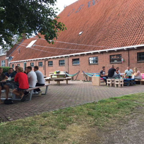 Personas sentadas al aire libre en Camping Pasveer, parque vacacional en Frisia, Países Bajos, disfrutando el día.