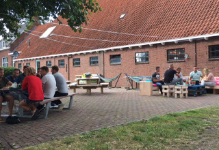 Udendørs opholdsområde ved Camping Pasveer i Friesland, Holland, med grupper, der nyder sommervejret.