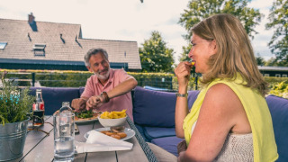 Una pareja mayor disfruta de una comida al aire libre en una mesa en un parque de vacaciones glamping.