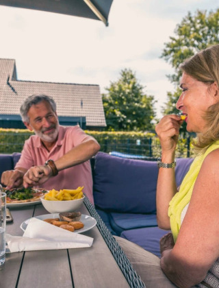 Una pareja mayor disfruta de una comida al aire libre en una mesa en un parque de vacaciones glamping.