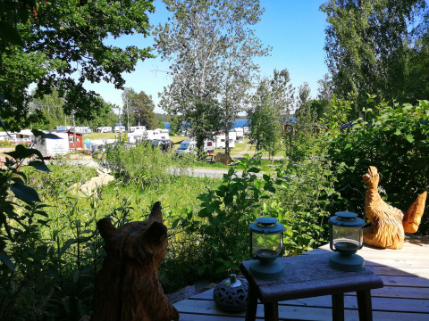 Udsigt over Camping Falkudden i Dalarna, Sverige, med campingvogne, træskulpturer og frodig natur.