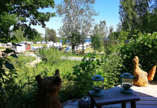 Vista su Camping Falkudden a Dalarna, Svezia, con roulotte, sculture in legno e vegetazione lussureggiante.