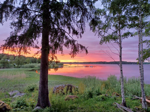 Atardecer en Camping Falkudden, Dalarna, Suecia, con lago tranquilo, árboles y cielo colorido reflejado.
