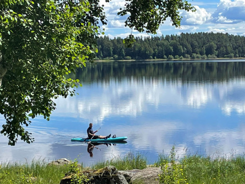 Un kayaker si gode una giornata tranquilla sul lago al Camping Falkudden, circondato dalla natura in Dalarna, Svezia.