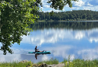 Un kayaker si gode una giornata tranquilla sul lago al Camping Falkudden, circondato dalla natura in Dalarna, Svezia.