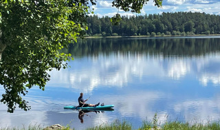 A kayaker enjoys a peaceful day on the lake at Camping Falkudden, surrounded by nature in Dalarna, Sweden.
