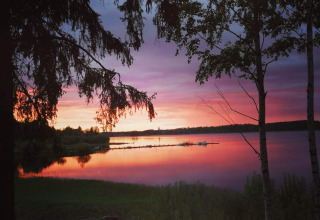 Splendido tramonto sul lago presso il Camping Falkudden holiday park a Dalarna, Svezia, tra gli alberi.