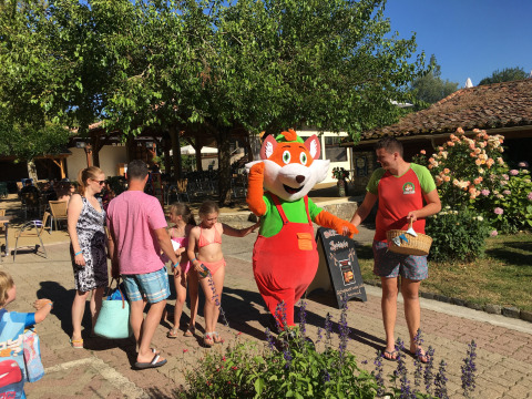 Familien treffen eine Maskottchenfigur im Freien im Ferienpark Le Camp de Florence, Occitanie, Frankreich.