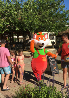 Familias saludan a la mascota y personal en el parque vacacional Le Camp de Florence en Occitania, Francia.