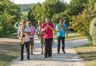 Cinque musicisti suonano strumenti all'aperto su un sentiero al Le Camp de Florence in Occitania, Francia.