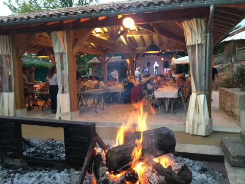 Repas en plein air et musique live autour du feu de camp au Camp de Florence, Occitanie, France.