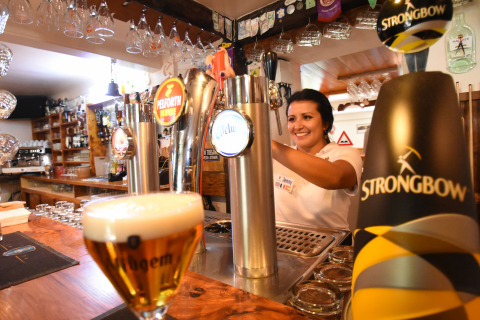 Een barvrouw schenkt tapbier in het vakantiepark Le Camp de Florence in Occitanië, Frankrijk.
