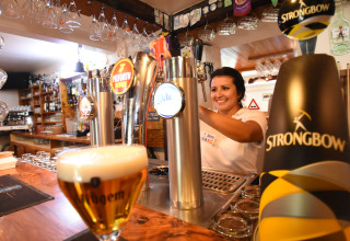 Een barvrouw schenkt tapbier in het vakantiepark Le Camp de Florence in Occitanië, Frankrijk.