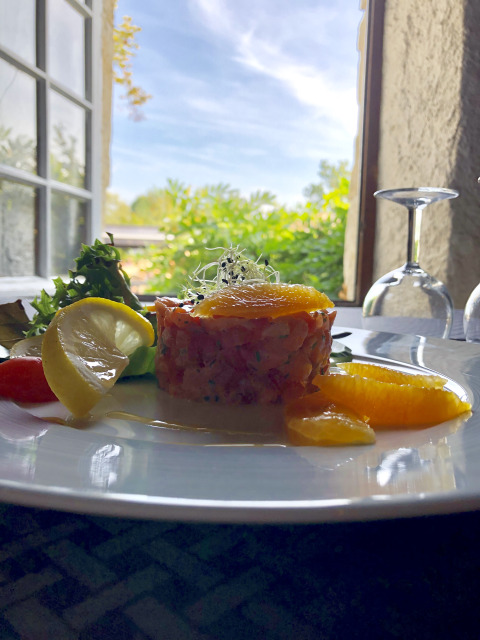 Gourmet dish with lemon and orange slices by an open window at Le Camp de Florence in Occitanie, France.