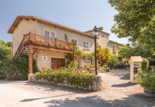Feriepark Le Camp de Florence i Occitanie, Frankrig med blomsterpyntet balkon, terrasse og grønne omgivelser.