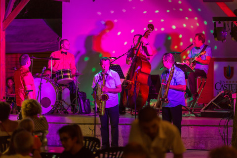 Banda en vivo actuando en un escenario iluminado en Le Camp de Florence, parque vacacional en Occitania.