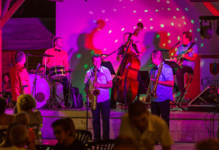 Band dal vivo si esibisce su un palco colorato a Le Camp de Florence, villaggio vacanze in Occitania.